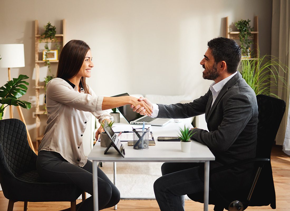Contact - View of a Smiling Middle Aged Agent Shaking Hands with a Female Client During a Meeting in the Office